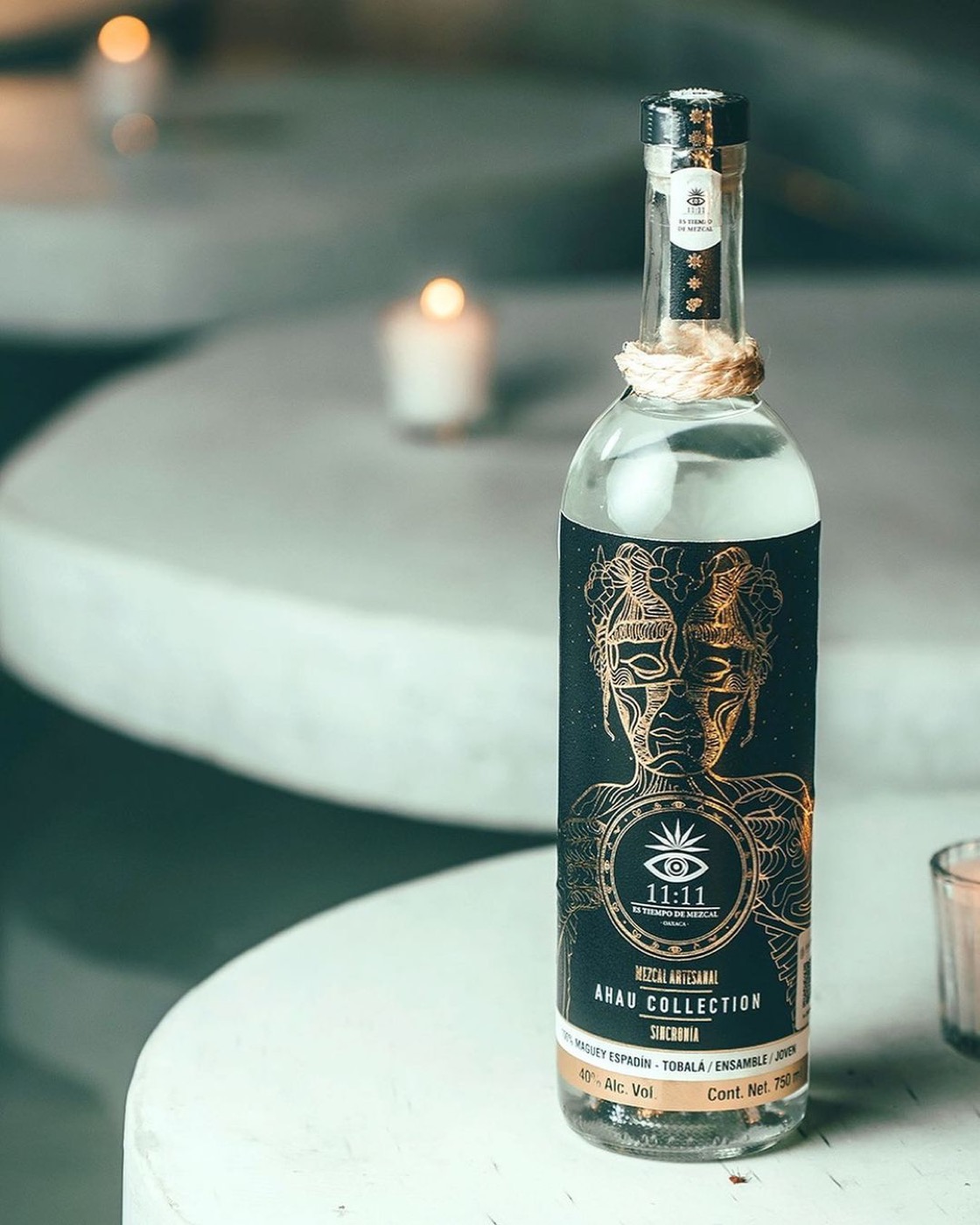 Botella Sincronía Ahau Collection sobre pedestales, ambiente ceremonial